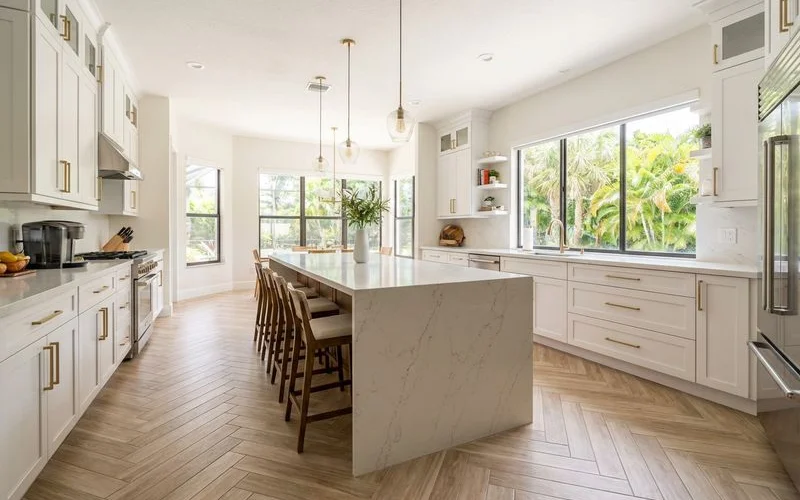 Herringbone pattern porcelain tile flooring installed in a bright Miami kitchen with white cabinetry